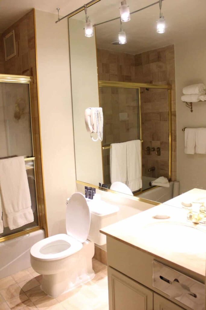 Kensington Park Hotel features luxurious bathrooms filled with bright lights and golden decor.