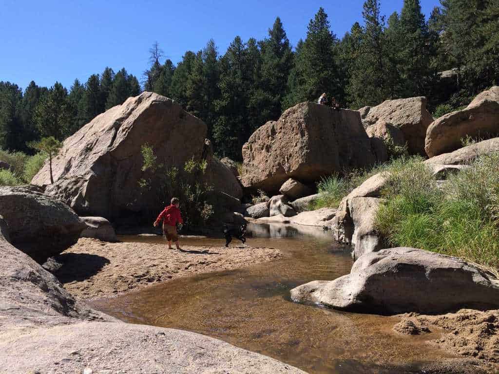 boy and dog splashing in stream at Castlewood Canyon State Park's Inner Trail