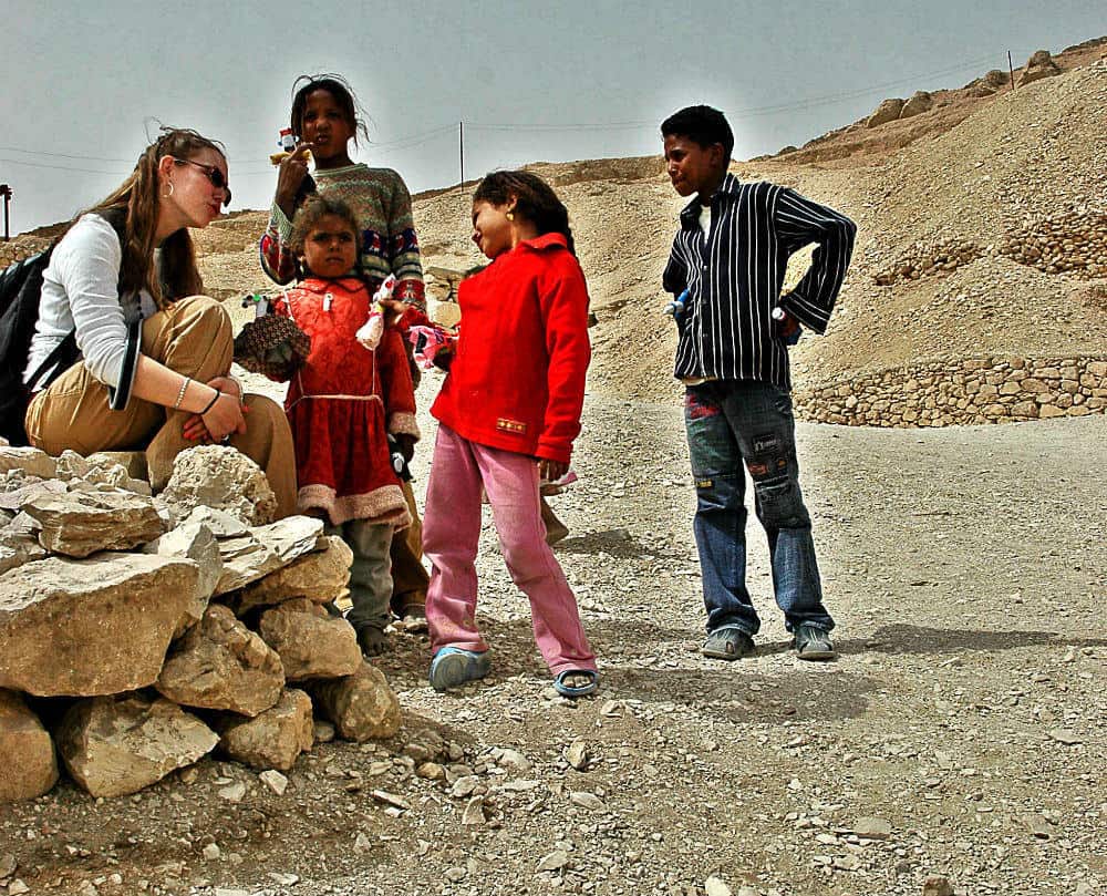 young female tourist with egyptian children in the desert