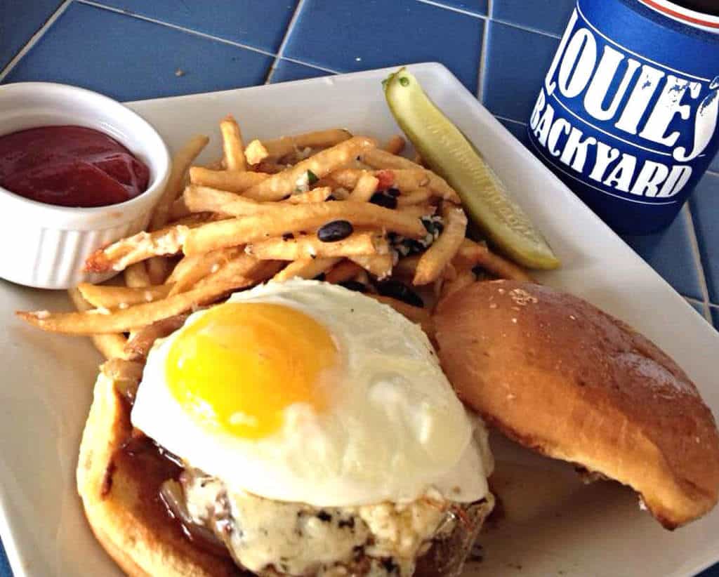 a hangover burger with fried egg beer and fries at louie's backyard on south padre island texas