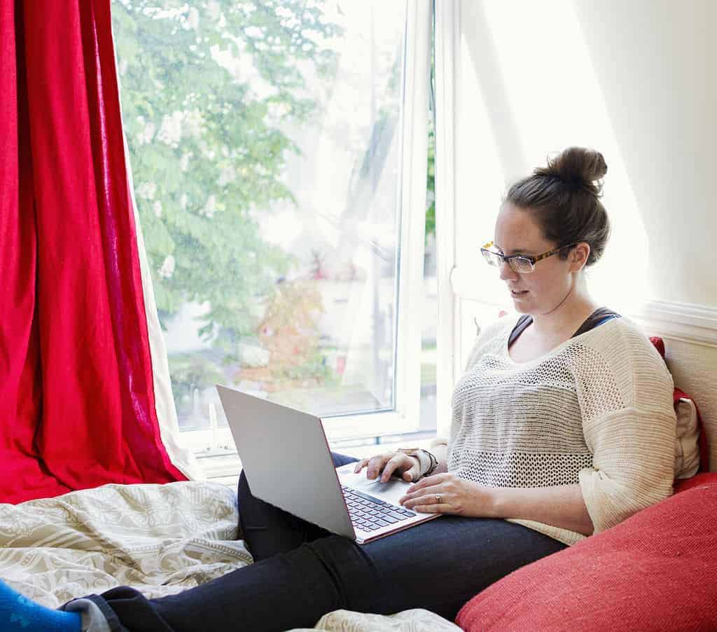 digital nomad jobs - eileen cotter wright by sunny window on bed with laptop