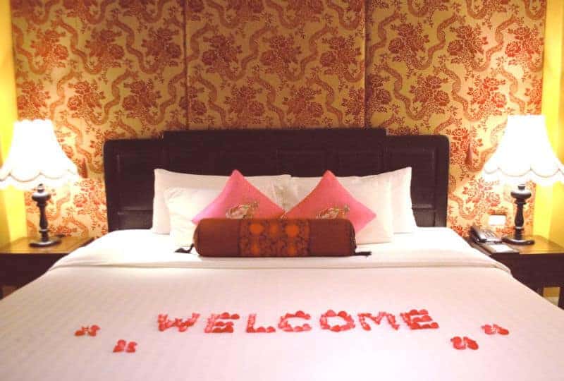 valentine day gift for girlfriend - hotel bedroom with rose pedals spelling welcome