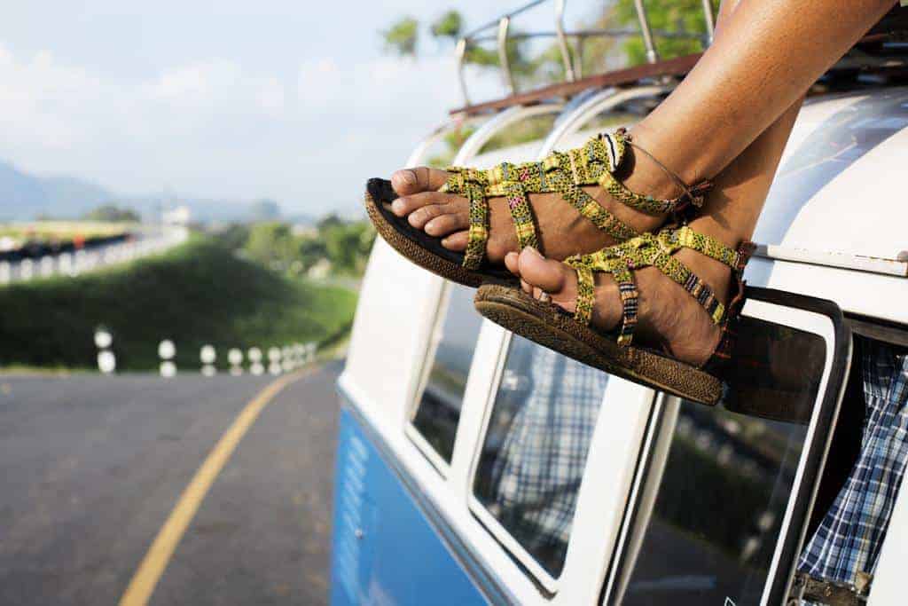 feet dangling on blue van on a paved road