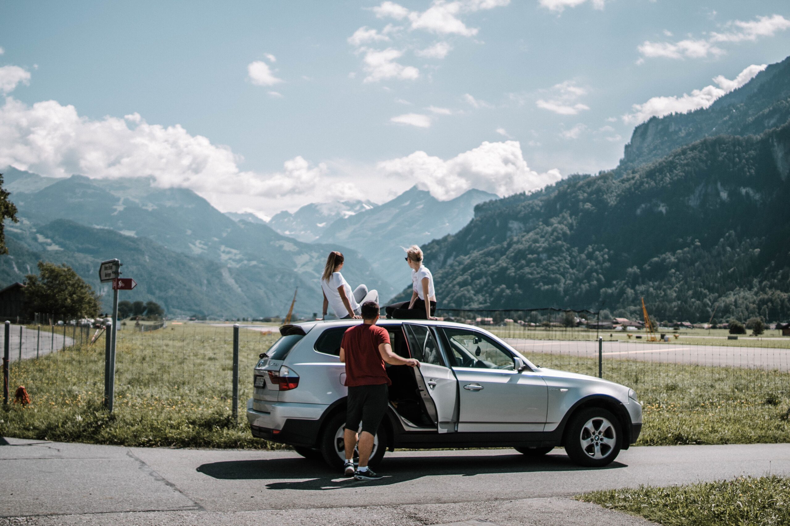 three people with an suv and mountains