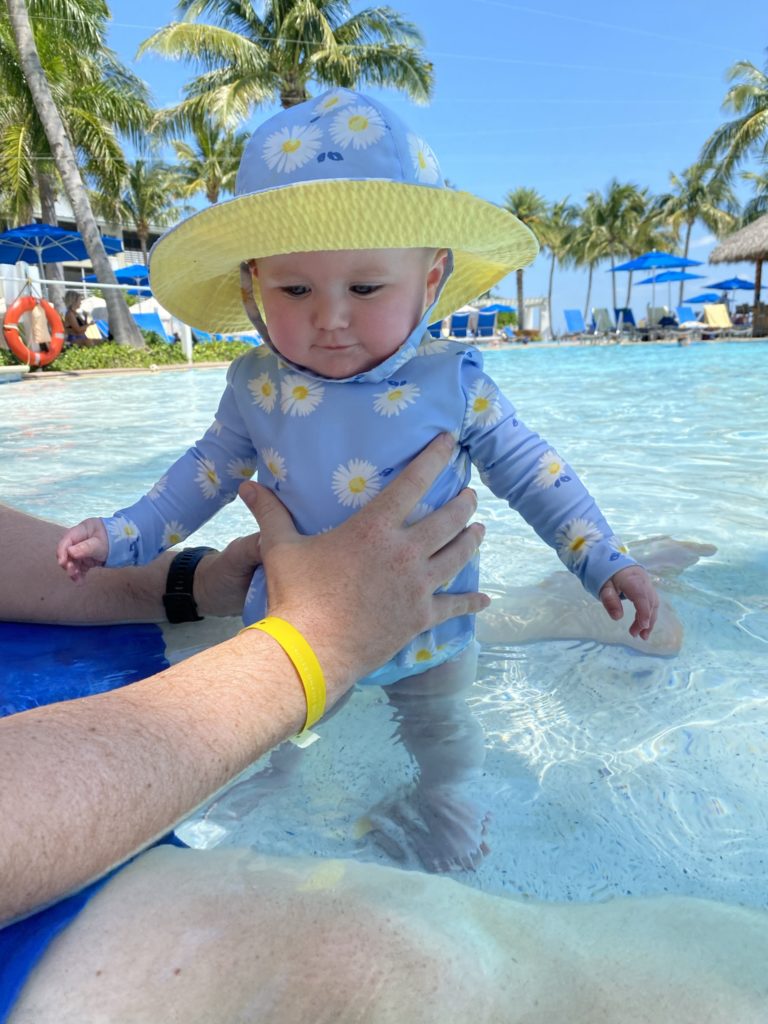 baby swimming in pool wearing daisy swimsuit rashguard