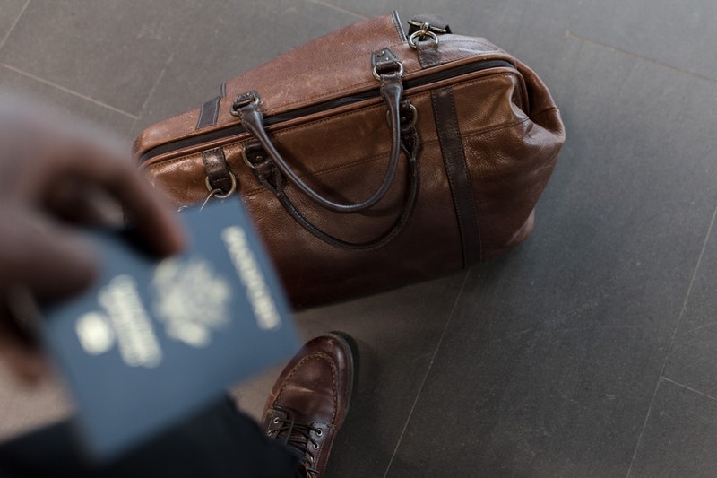 brown leather luggage and passport