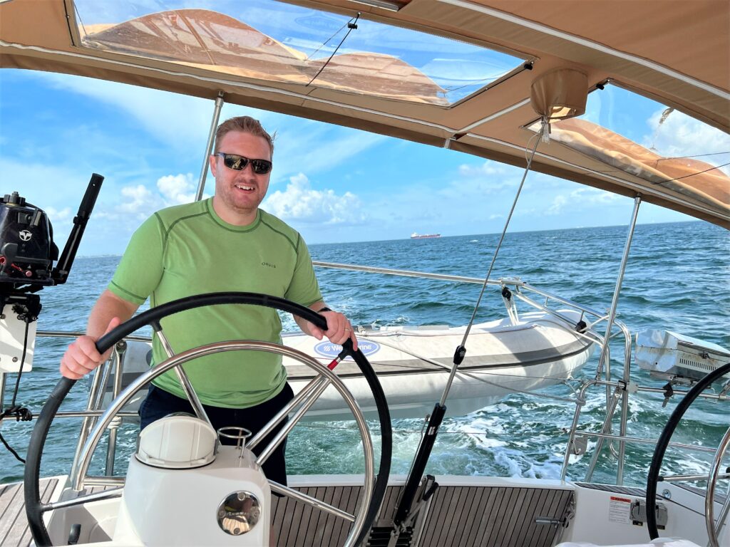 christian steering a sail boat with offshore